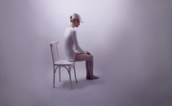 donna sola vestita di bianco seduta su una sedia bianca