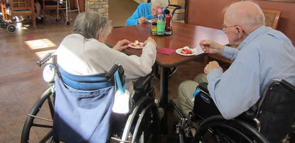 due anziani in carrozzina, all'interno di una casa di riposo, visti di spalle