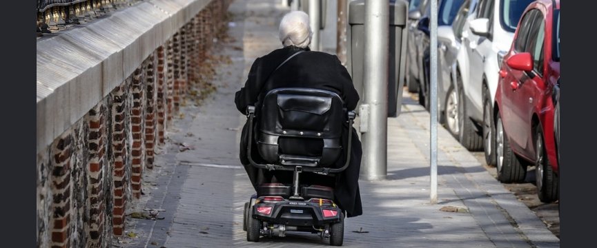 anziano di spalle in scooter