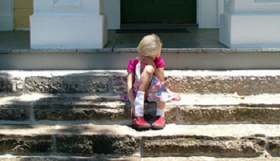 bambina triste che piange sulle scale di una casa