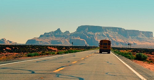 scuola bus su strada e sullo sfondo cielo sereno e montagne