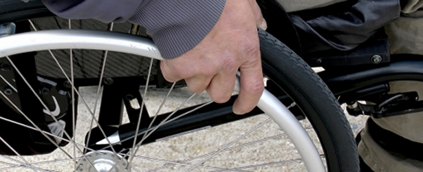 dettaglio della mano di una persona sulla ruota di una sedia a rotelle