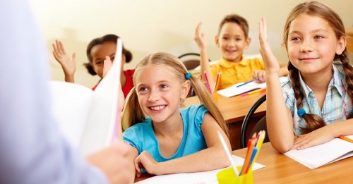 bambini in classe con mani alzate