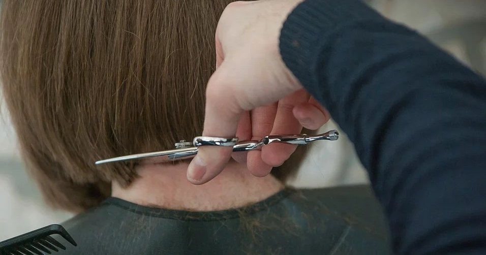 dettaglio delle mani di una persona che taglia i capelli ad un'altra