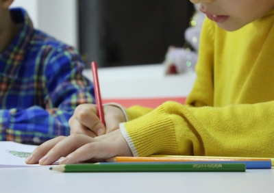 bambino che scrive con una matita rossa