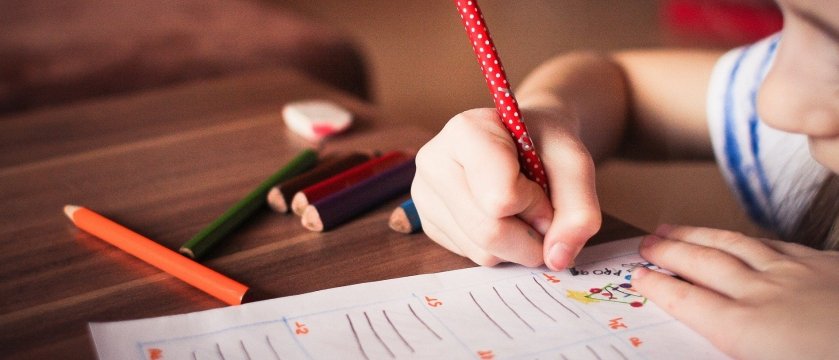 dettaglio delle mani di un bambino che colora su un quaderno