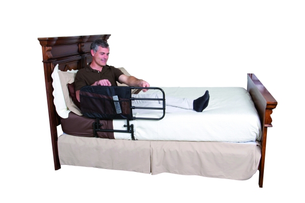 uomo steso a letto regola in lunghezza la sponda telescopica che è applicata al lato del letto