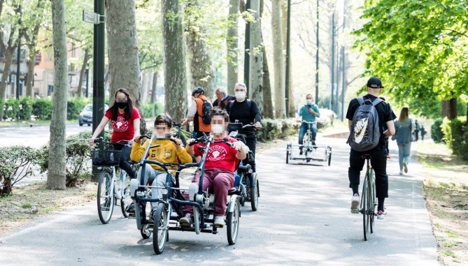 su una pista ciclabile, insieme ad altri ciclisti, anche una bici con un paio di ragazzi con disabilità