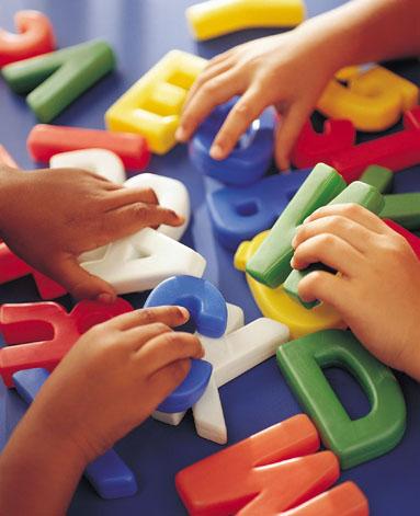 mani di bambini che giocano con lettere giocattolo