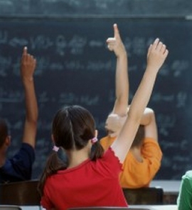 scuola: bambini in classe con mani alzate 