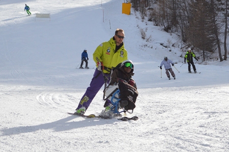 un istruttore fa sciare un ragazzo in modalità sitting