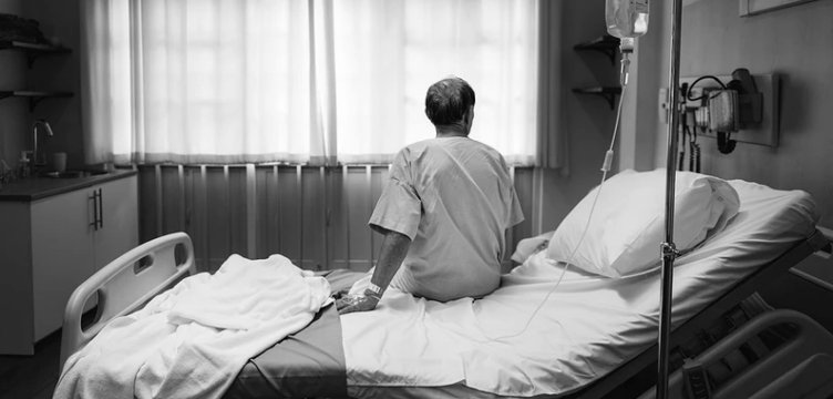 anziani di spalle seduto sul letto in una camera d'ospedale