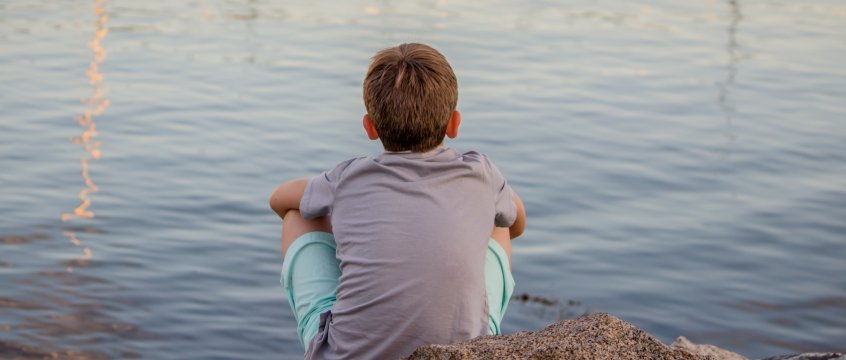 bambino seduto di fronte al lago