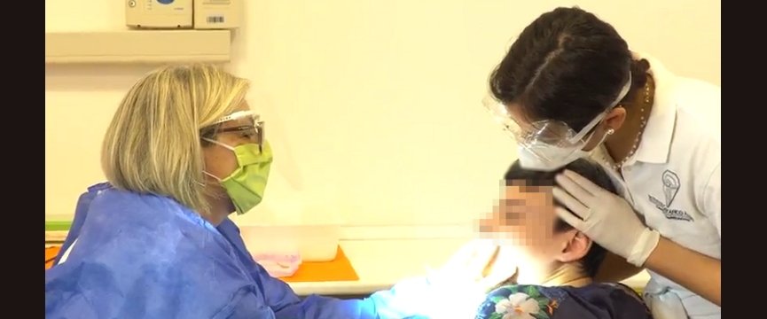 medico effettua una visita dentistica a un ragazzo con l'aiuto di una assistente