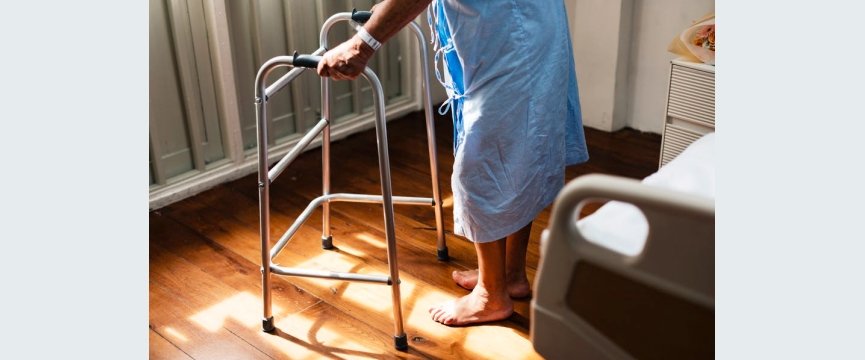 una signora anziana si alza dal letto d'ospedale grazie al suo girello