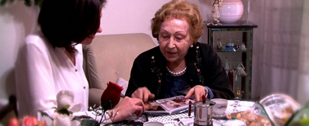 un'anziana signora guarda delle foto in salotto con la figlia