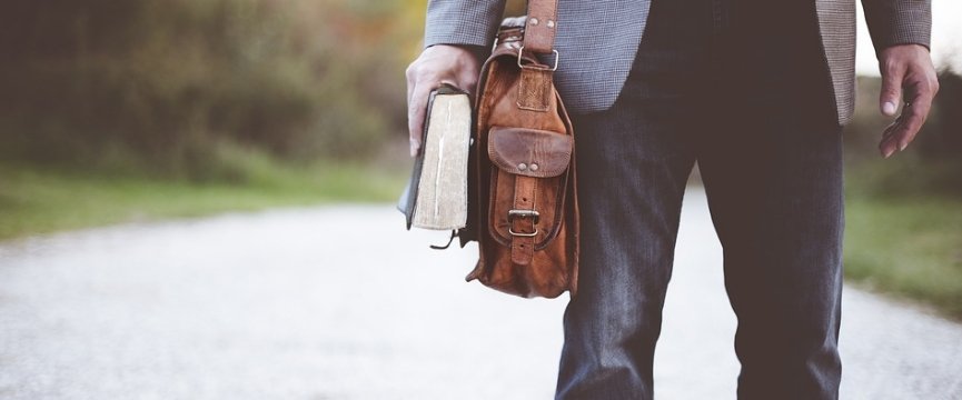 un uomo con una borsa di pelle che tiene un libro chiuso in mano