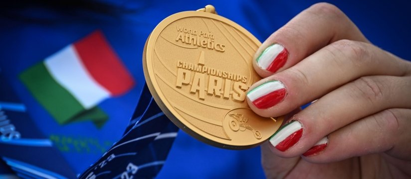 dettaglio di una medaglia d'oro dei mondiali di atletica, tenuta in mano da una persona con smalto tricolore