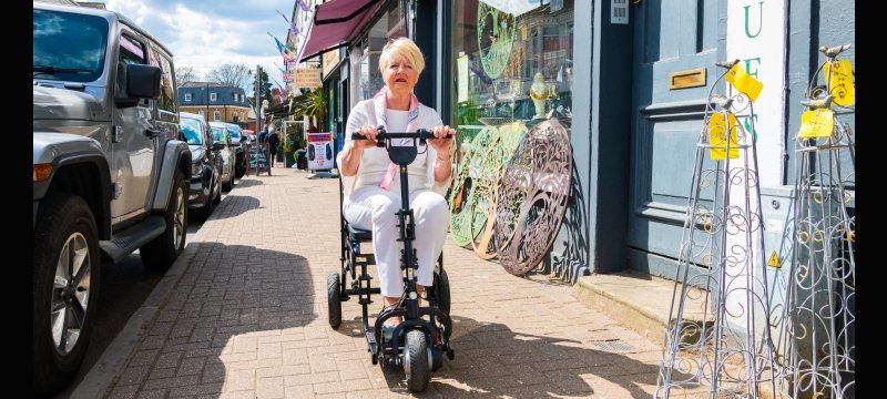 signora anziana mentre gira per la città con uno scooter elettrico