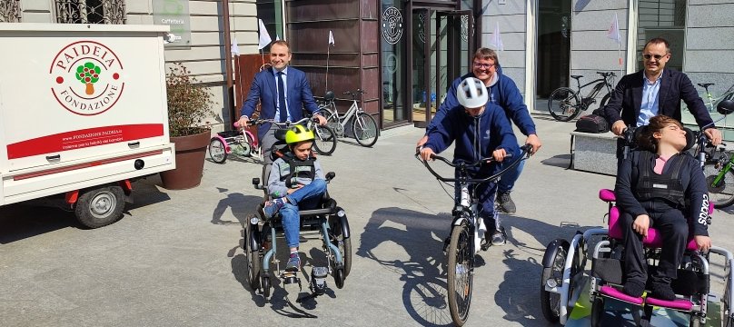 tre adulti a bordo di bici adattate per ragazzini con diverse disabilità