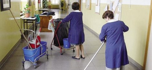 due signore, impiegate ATA, impegnate a lavare il pavimento di un corridoio scolastico