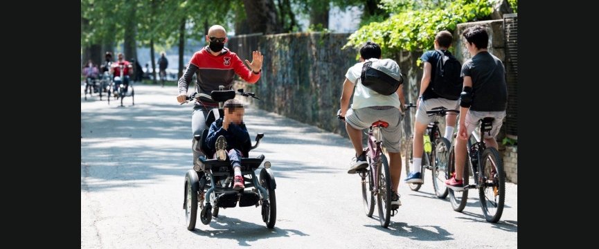 adulto porta in giro in bici un ragazzino con disabilità