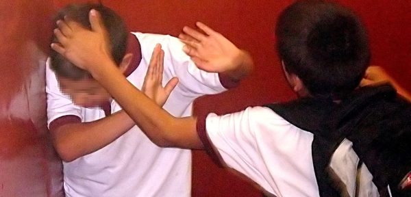 un ragazzino fotografato mentre malmena un suo compagno di classe dopo averlo messo all'angolo