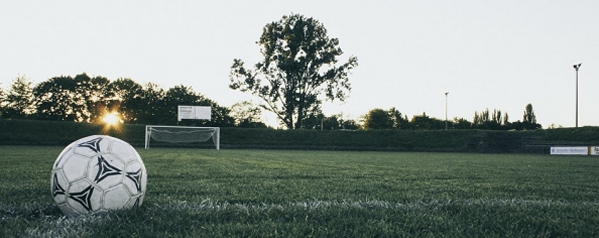 campo da calcio al tramonto con pallone sull'erba