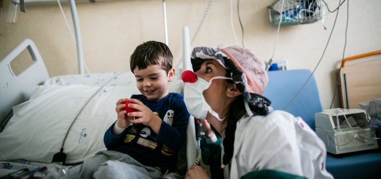 ragazza vestita da clown gioca con un bambino in ospedale