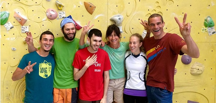 gruppo di atleti scalatori ciechi e istruttrice, sullo sfondo una parete attrezzata per la scalata