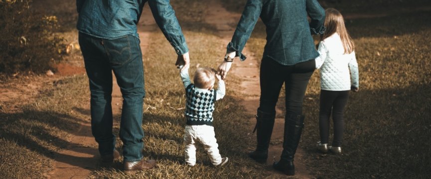 famiglia con genitori e due bambini piccoli di spalle, mentre cammina