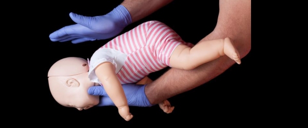 operatore fa esercizi di disostruzione pediatrica con bambolotto