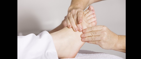 dettaglio delle mani di un fisioterapista sul piede di una persona