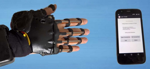 mano maschile coperto da un guanto robotico che si avvicina ad uno smartphone