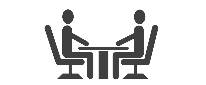 scrivania con due persone sedute una davanti all'altra 