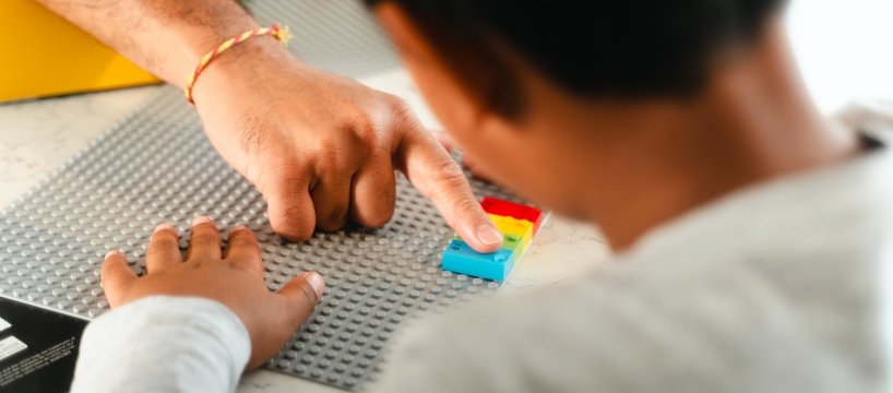 dettaglio delle mani di due bambini che giocano con i mattoncini lego braille 