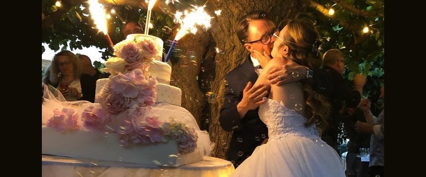 Simone Sciarrini e Lorena Chiesa si abbracciano vicino alla torta nel giorno del loro matrimonio