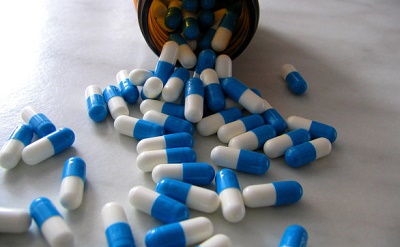 contenitore di medicine aperto con pillole versate su tavolo