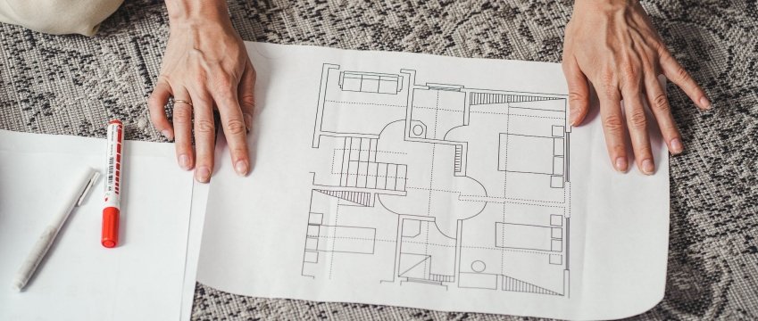 dettaglio delle mani di una donna sul disegno tecnico di un edificio
