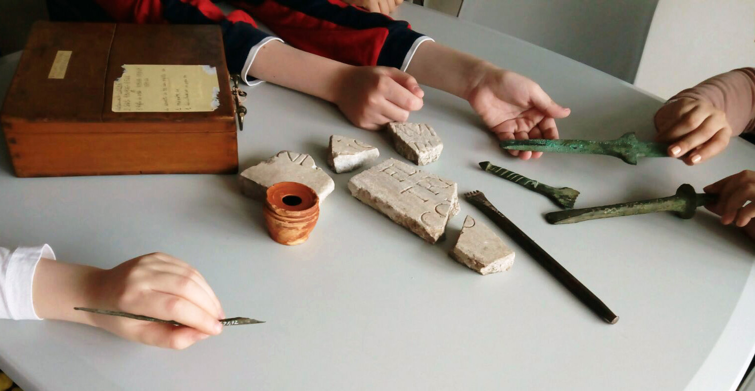 dettagli di mani di bambini che toccano reperti archeologici