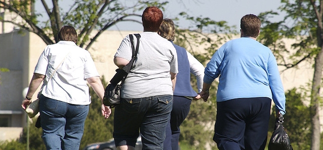 quattro uomini visibilmente molto obesi che camminano, visti di spalle
