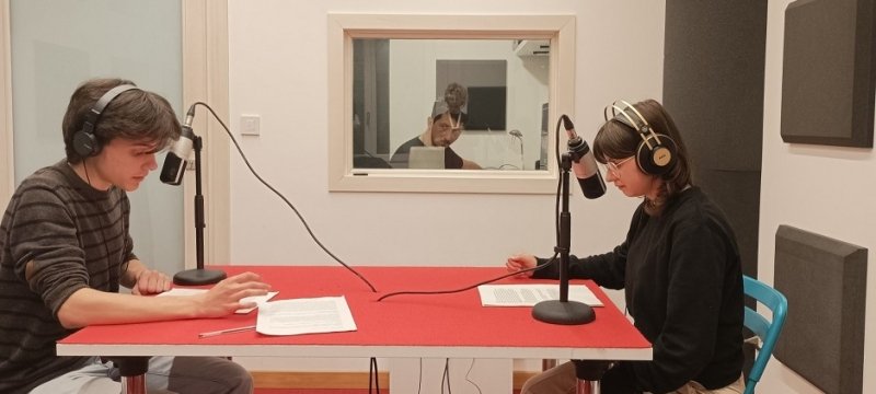 due ragazzi con cuffie al tavolo mentre registrano un podcast