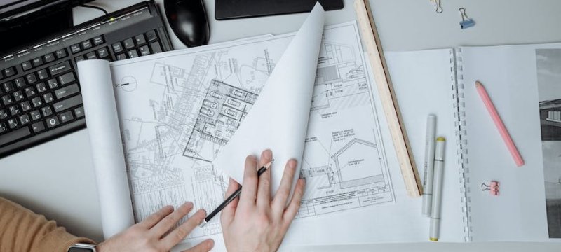 dettagli delle mani di una persona su alcuni disegni tecnici di edifici