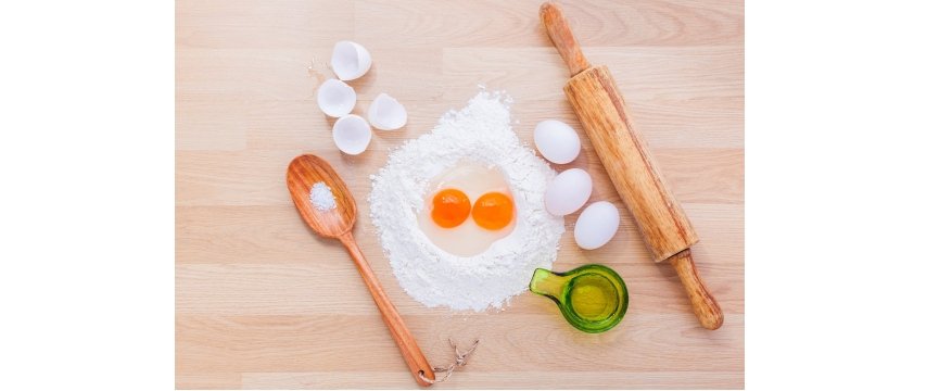 uova, farina e altri ingredienti e utensili di cucina su un tavolo di lavoro