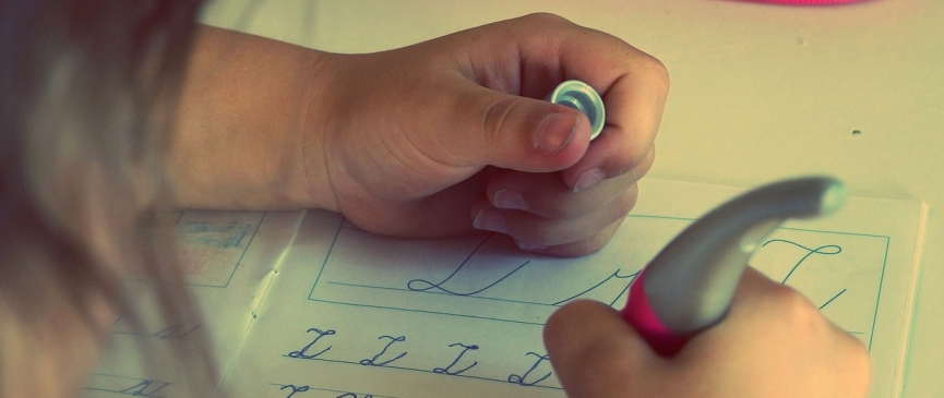 bambina che scrive delle lettere sul quaderno