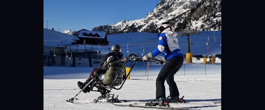 istruttore sugli sci insieme ad una persona seduta sul monosci