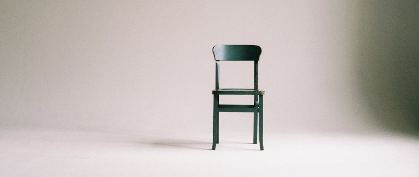 una sedia verde in mezzo ad una stanza grande e vuota