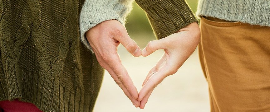 due persone uniscono le mani in modo da formare il simbolo di un cuore