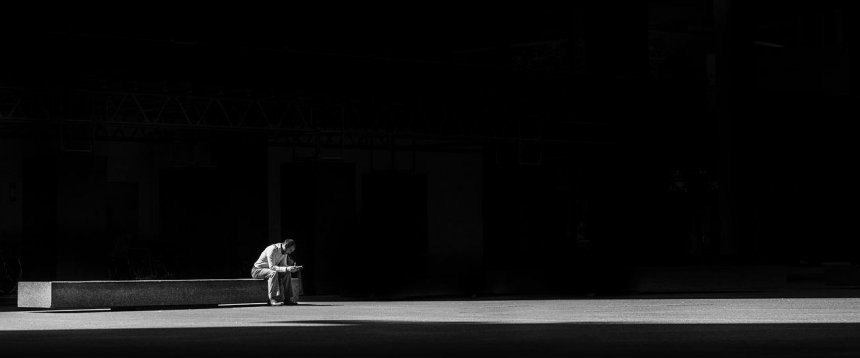 uomo seduto in solitudine in uno spazio completamente vuoto