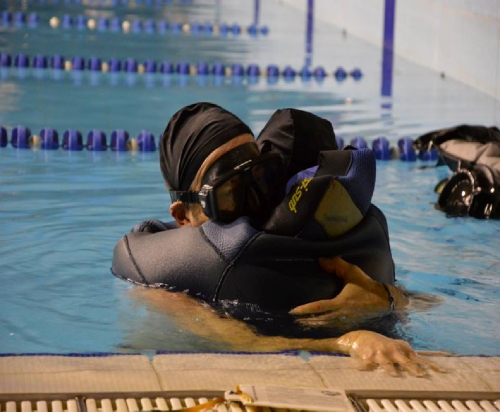 donna in piscina con muta da sub abbraccia un amico